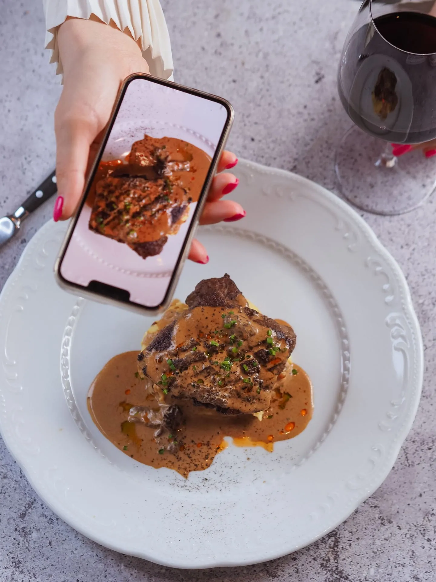 Pessoa fotografando um prato com o celular em uma mesa de restaurante