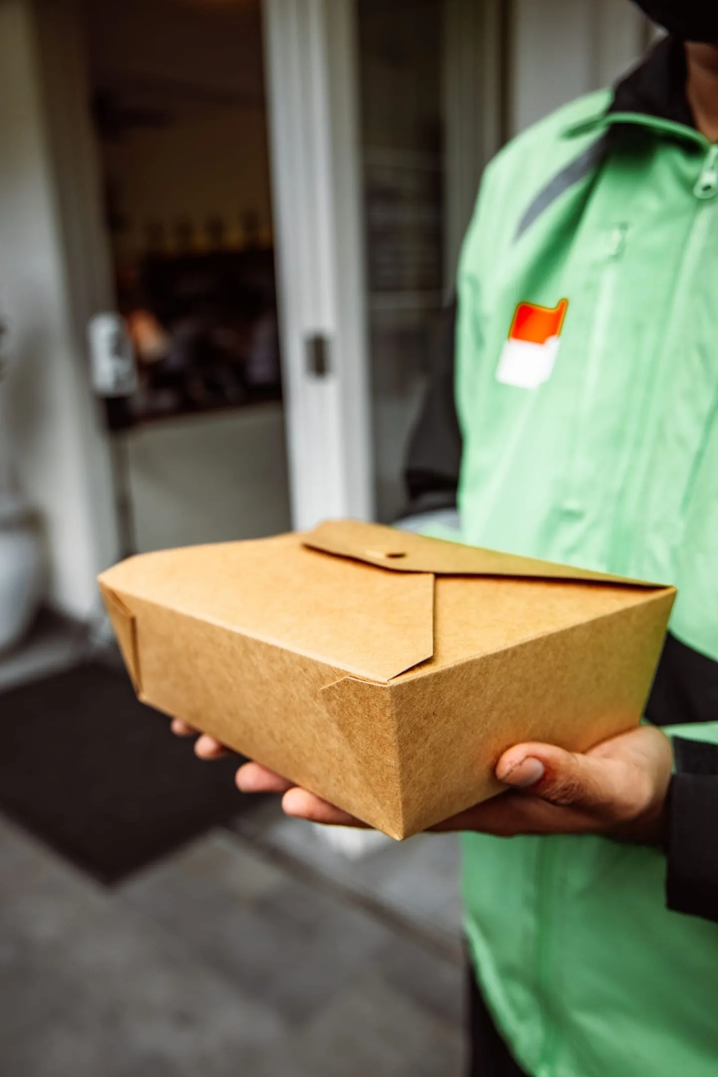 Repartidor con una bolsa de papel de comida afuera de un restaurante