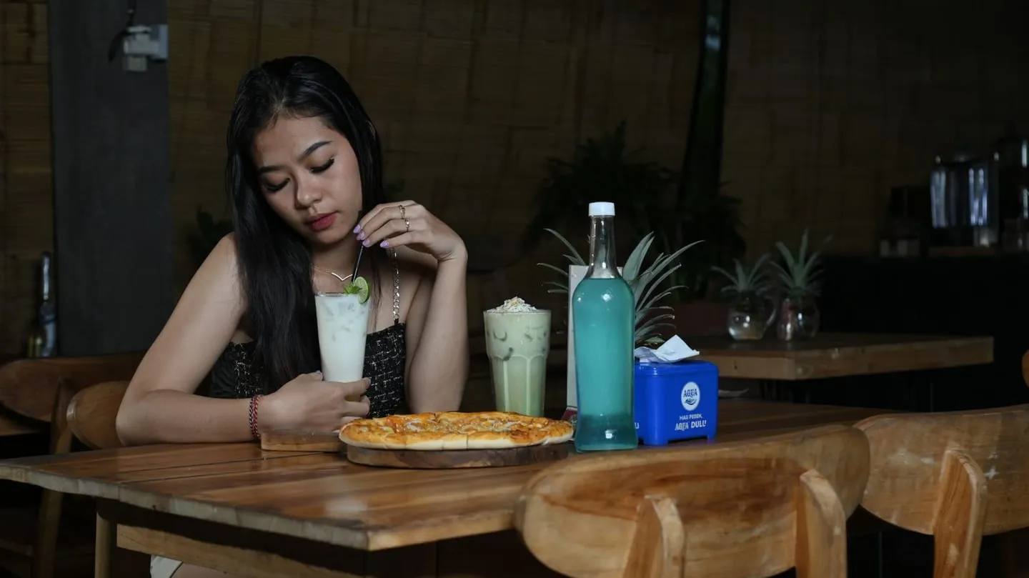 Seorang perempuan menikmati minuman di sebuah restoran di Denpasar, Bali