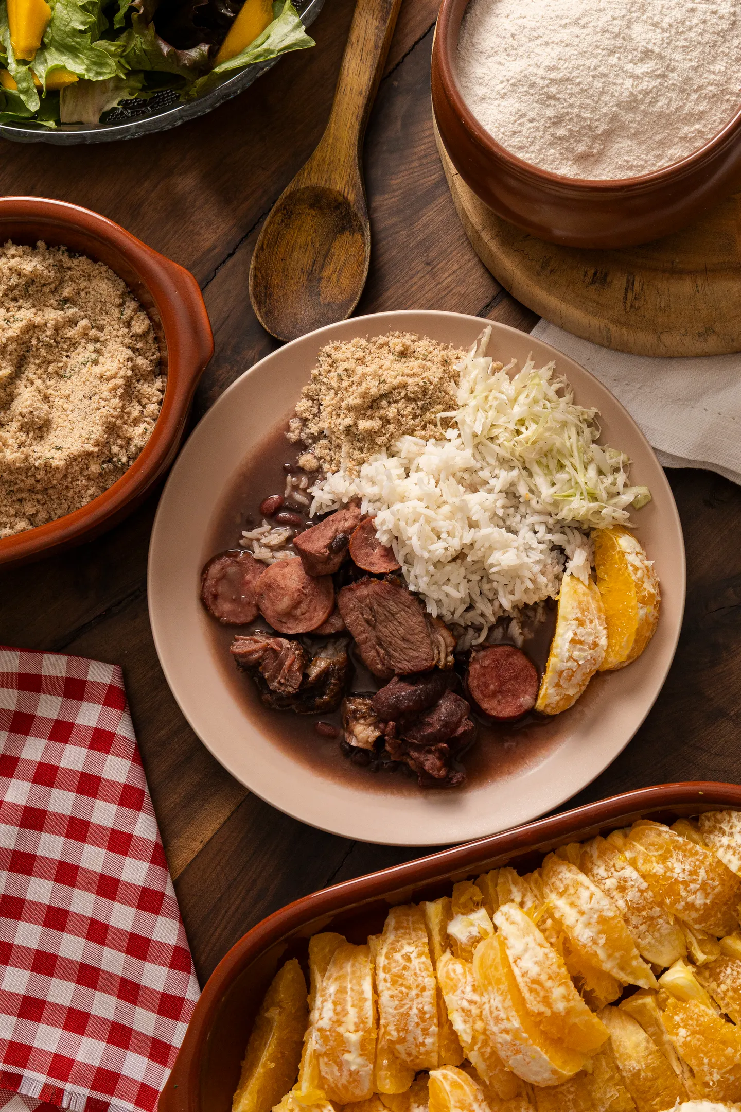 Feijoada completa servida com farofa, laranja e salada