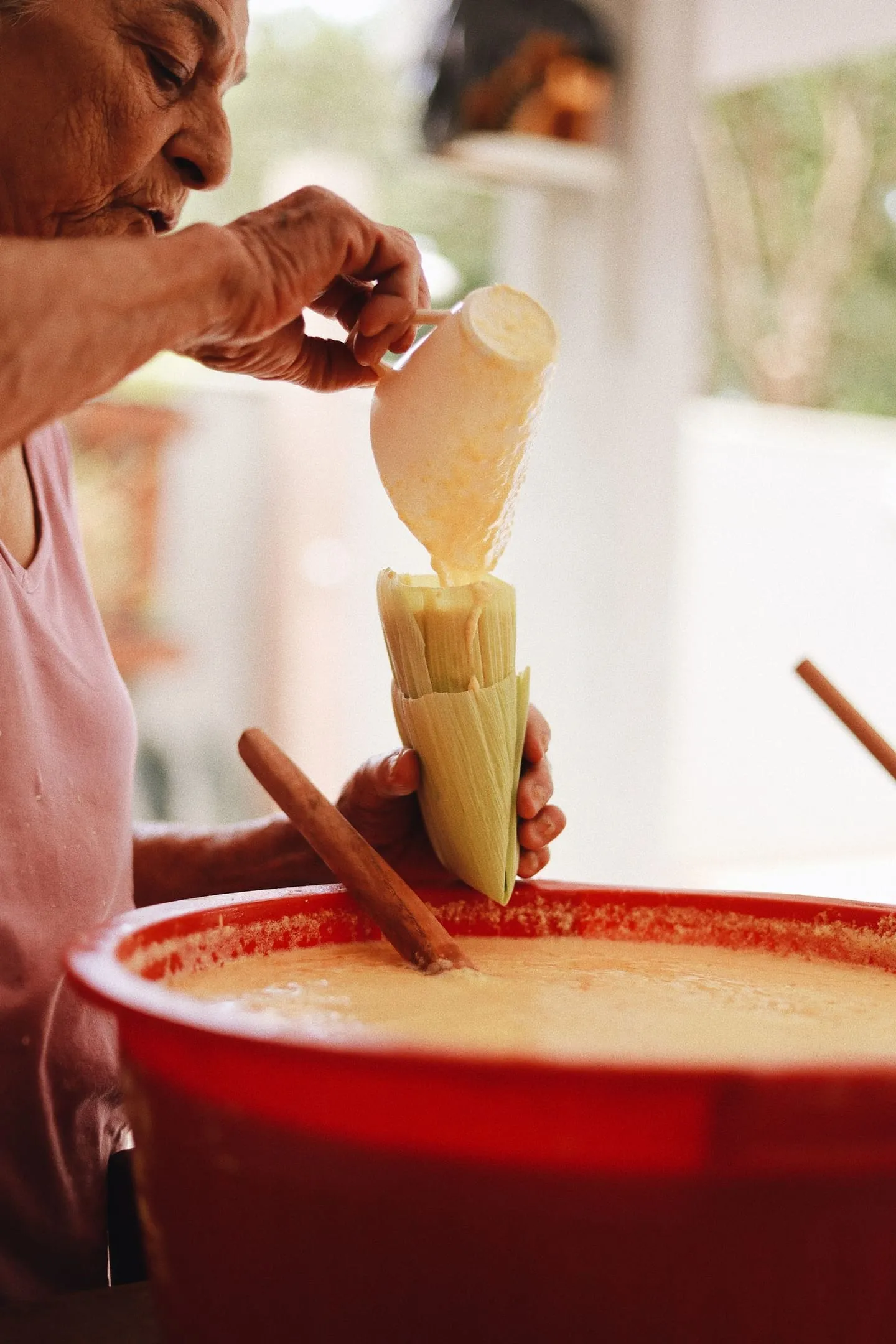 Mulher preparando pamonha com milho em uma cozinha