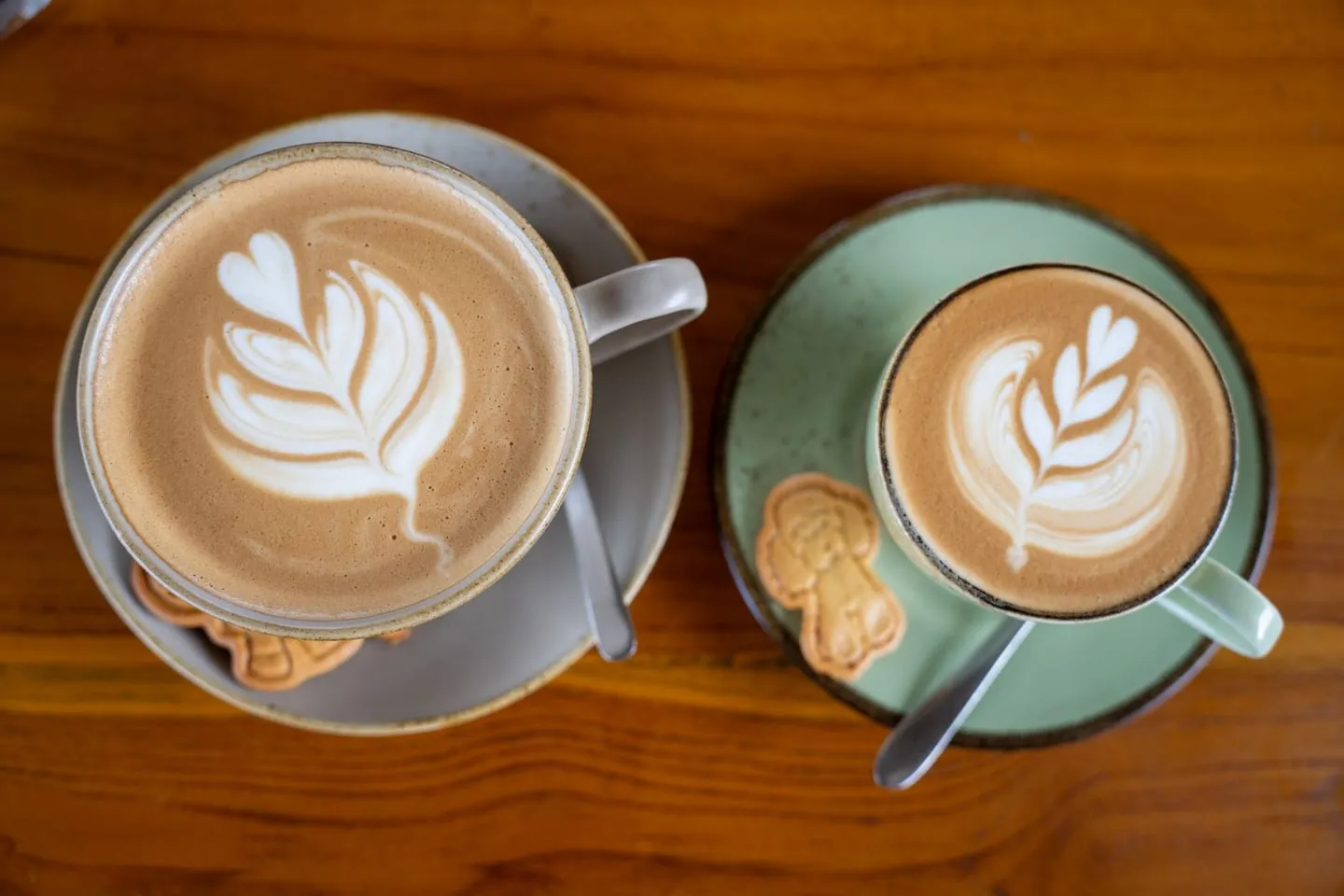 Dua cangkir latte dengan kue di atas meja kayu di Bali