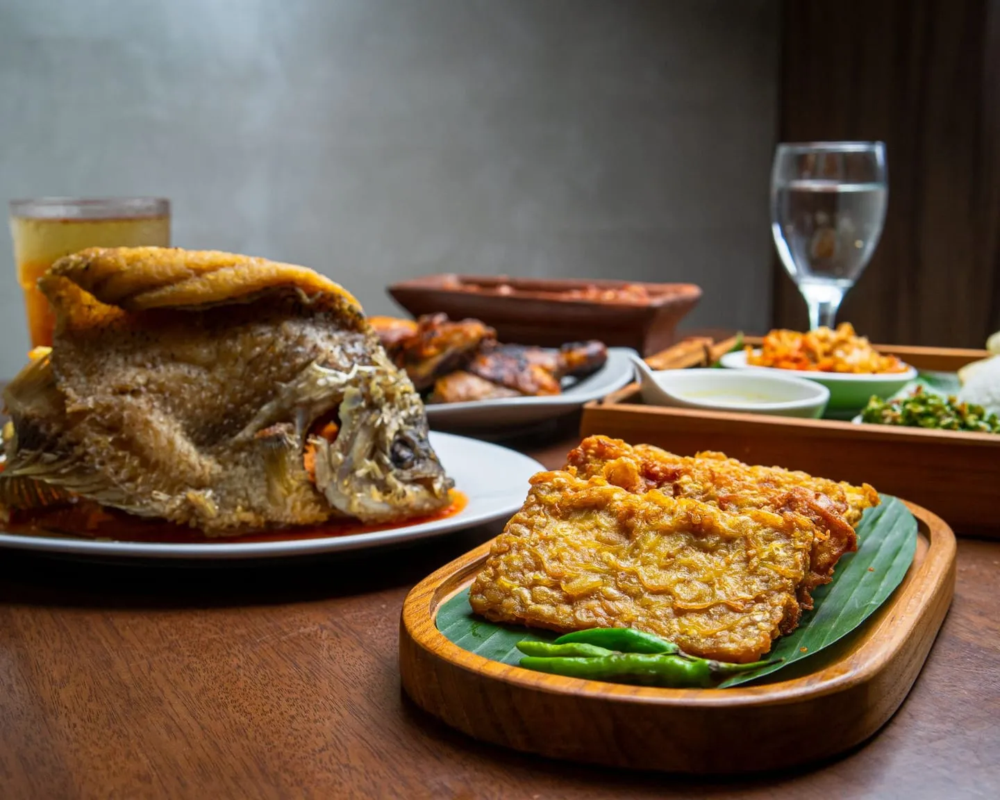 Ikan goreng dan tempe, hidangan tradisional Indonesia di atas meja kayu