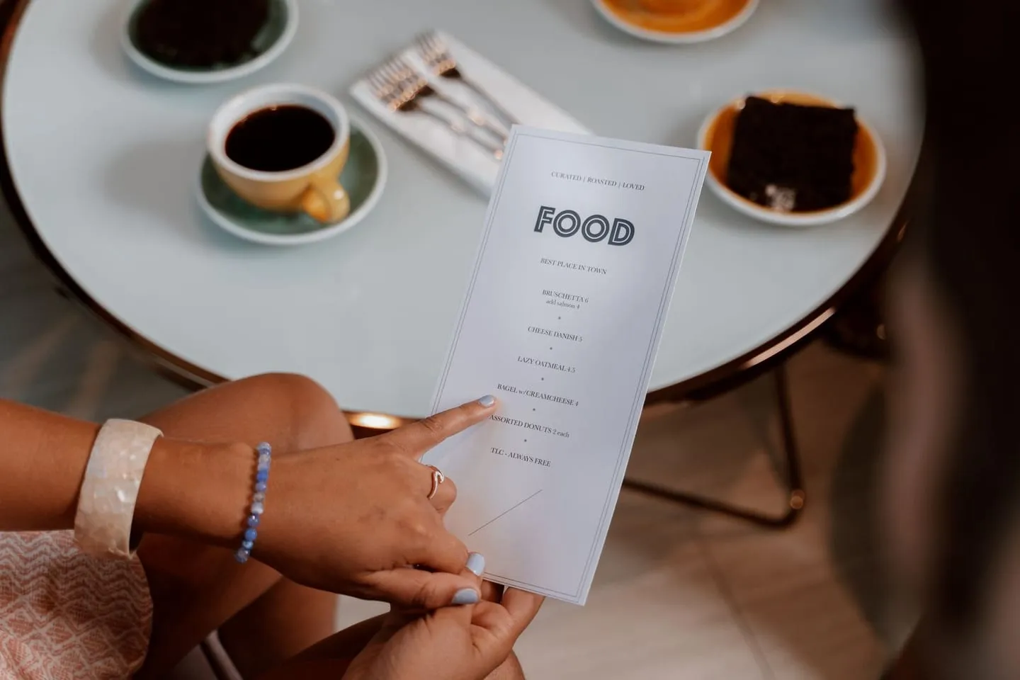 Hands holding a menu at a cozy cafe with coffee